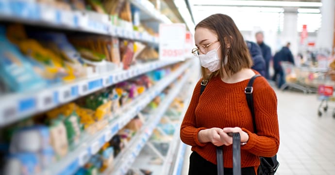 A young woman wearing cloth mask browses items at a pharmacy