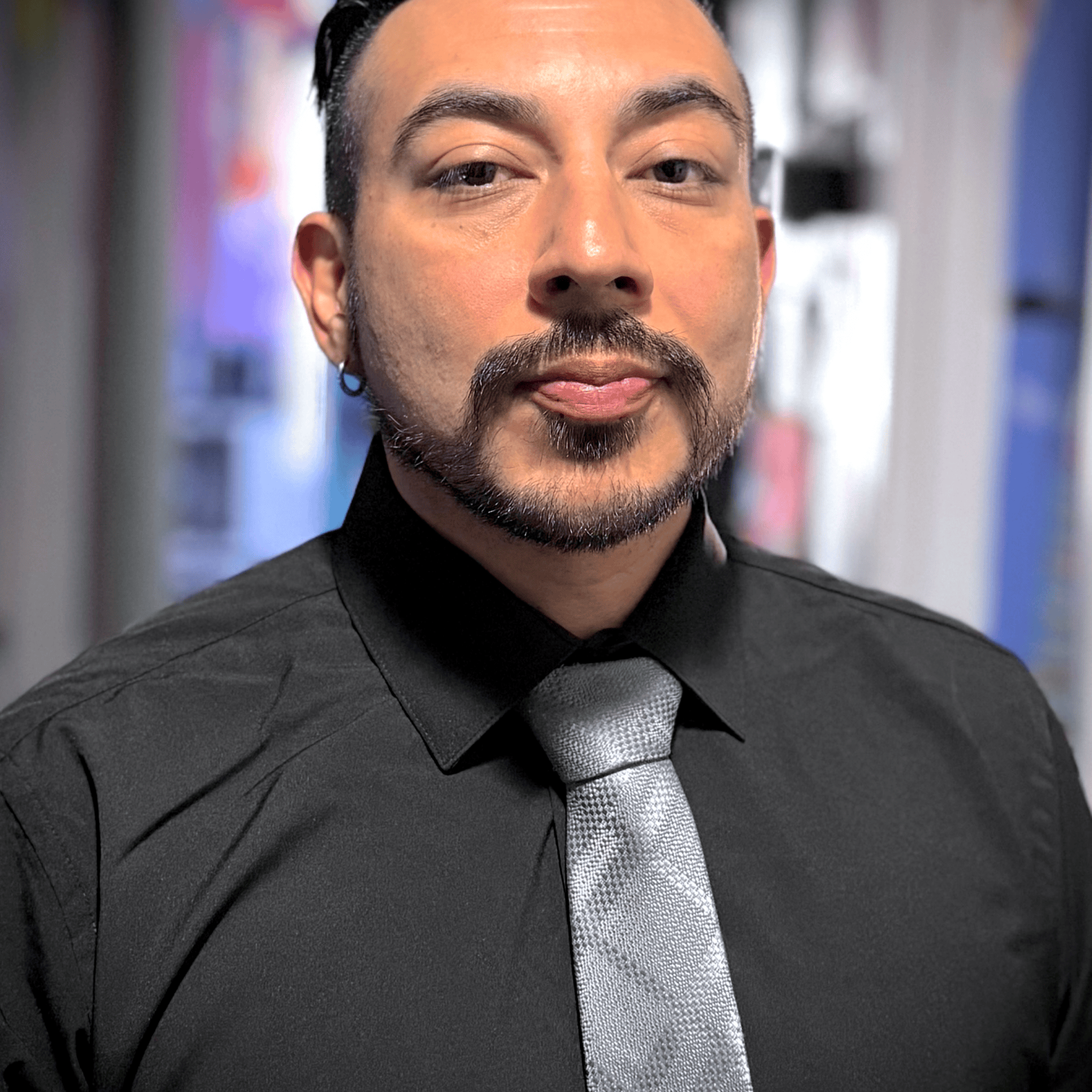 Confident man in black shirt and gray tie, professional appearance.